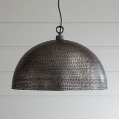 a metal light hanging from a ceiling in a room with white walls and wood flooring