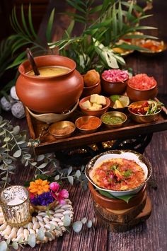 several bowls filled with food sitting on top of a wooden table next to potted plants