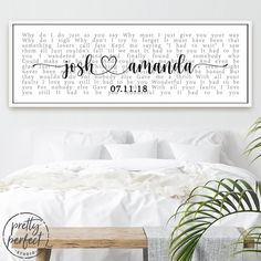 a bed with white sheets and pillows in front of a wall mounted canvas that reads just married