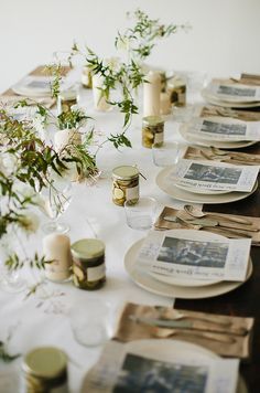 an image of a table setting with place settings and flowers in vases on it