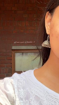 a close up of a person wearing some kind of earring with brick wall in the background