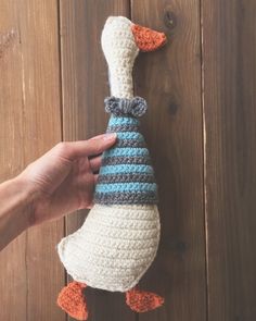 a hand holding a crocheted duck with a hat on it's head