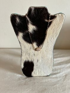 a cowhide necklace holder on a white sheet