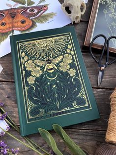 a green book sitting on top of a wooden table next to scissors and other items