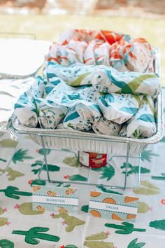 some cloths are sitting in a metal tray on top of a white tablecloth