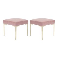 a pair of pink velvet stools with gold frame legs and foot rests on white background