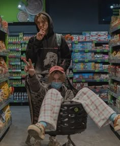 two people in a grocery store with masks on and one person sitting in a shopping cart