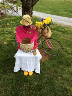 a woman sitting on a bench next to a bike with flowers in the basket and yellow shoes