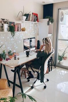 a woman sitting at a desk in front of a computer monitor on top of a white table