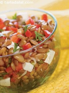 a glass bowl filled with beans and veggies on top of a yellow cloth