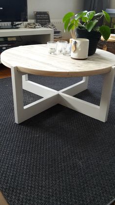 a white coffee table with a plant on top in front of a flat screen tv