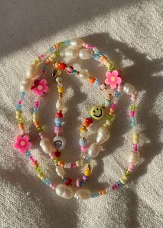 two bracelets with flowers and beads are on the ground next to a white towel