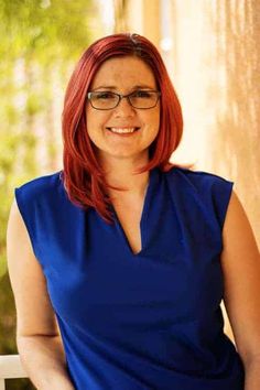 a woman with red hair and glasses is smiling