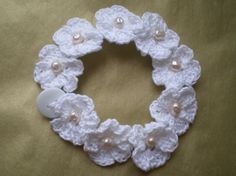 a white crocheted bracelet with buttons and pearls on it's center piece