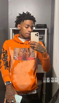 a man in an orange hoodie looking at his cell phone