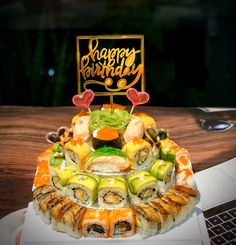 a sushi platter on a table with a happy birthday sign in the background