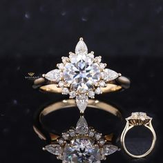 an engagement ring with two pear shaped diamonds on the side, and a flower - shaped diamond in the middle