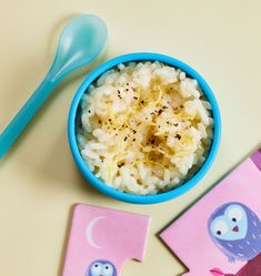 a bowl of rice next to two cards and spoon