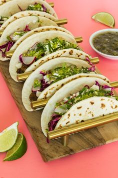 several tacos are lined up on a wooden board