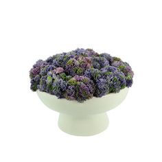 a white bowl filled with purple flowers on top of a table