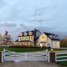 a large white house sitting on top of a lush green field under a cloudy sky