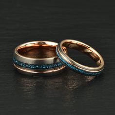 two gold wedding bands with blue glitter inlays on each band, set against a black background