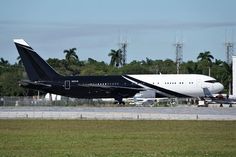 an airplane on the tarmac with another plane in the background and trees behind it