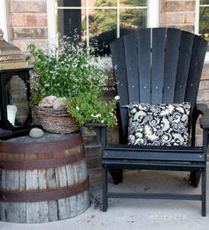 two chairs sitting on the front porch next to a potted plant and an old barrel