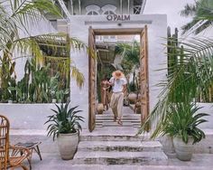 a man walking up the stairs to a building with palm trees in front of him