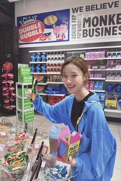 a woman holding up a cell phone in front of a store display filled with items