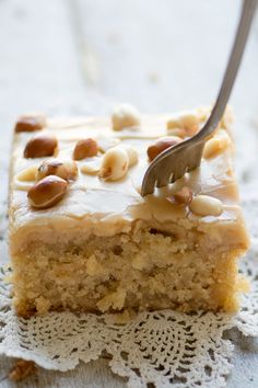 a piece of cake on a doily with a fork stuck in it and nuts