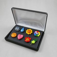 a black box with seven different colored plastic objects in it's lid and inside