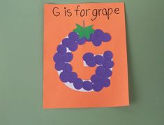 a handmade letter g is for grape on an orange paper with purple grapes and green leaves