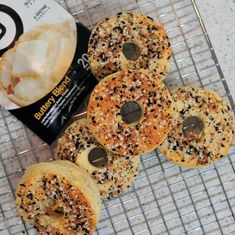 bagels with sprinkles are sitting on a cooling rack next to a packet of potato chips