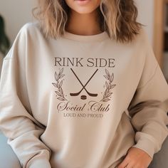 a woman sitting on a couch wearing a sweatshirt with the words rink side social club printed on it