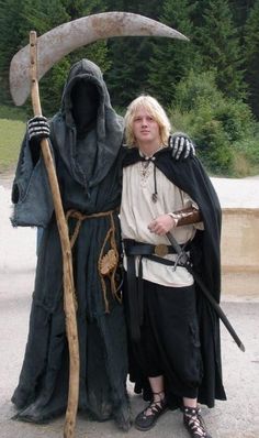 a woman standing next to a man dressed as an old wizard holding a sceptula