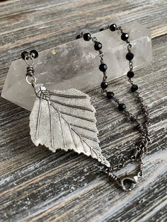 Special handmade item, one of a kind.  This brambly, woodsy piece is the connotation of forest undergrowth translated into a wearable statement necklace with the elegance of classic silver and black. The centerpiece is a large double-sided antiqued silver leaf pendant measuring just under 3"x2.75". The chain length, measuring 22", is all hand wire wrapped rosary style connections patterned with segments of 5mm faceted black glass rounds and varying thick "messy" accents. Hand wire-wrapped findings/clasping ring loops have hand-hammered finishes.  Metals are quality and nickel safe. The wire is gunmetal finished 16 gauge copper wire with a nylon tarnish-proof coating. Pendant is zinc alloy based with antiqued silver finish.  This piece is definitely sturdy, but if a connection gets kinked, Handmade Black Nature-inspired Jewelry, Handmade Nature-inspired Black Jewelry, Black Nature-inspired Jewelry, Artisan Black Soldered Necklace, Forest Undergrowth, Wire Wrapped Chain, Necklace Gothic, Wrapped Necklace, Handmade Wire Wrapped