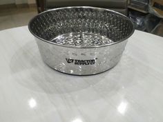 a metal bowl sitting on top of a white table