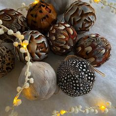 a bunch of different types of ornaments on a white table cloth with lights around them