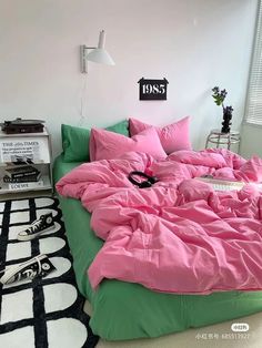 a bed with pink and green sheets in a room next to a black and white rug