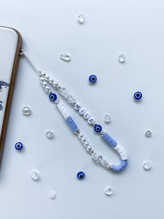 a cell phone with an evil eye beaded necklace attached to it next to some beads