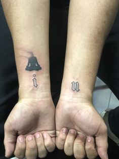 two people with matching tattoos on their arms holding hands in the shape of a bell