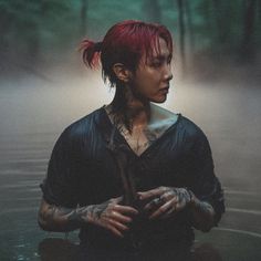 a woman with red hair and tattoos standing in the water holding her hands out to her chest