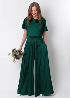 a woman in a green jumpsuit holding flowers