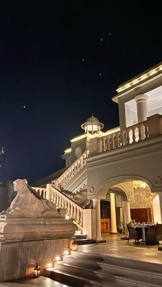 a large building with stairs leading up to it and lit up lights on the side