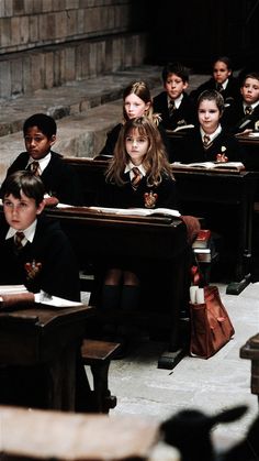 a group of children sitting at desks in a classroom with their backs to the camera