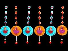 colorful paper fan decorations hanging from strings on black background with red, orange and blue accents