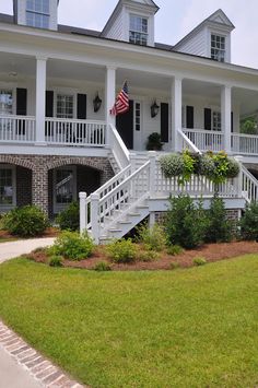 a large white house with an american flag on it's porch and stairs leading up to the front door