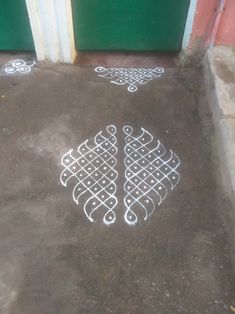 two white designs on the ground next to a green door