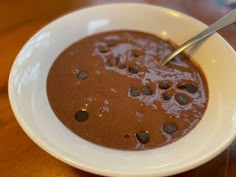 a white bowl filled with chocolate pudding on top of a wooden table